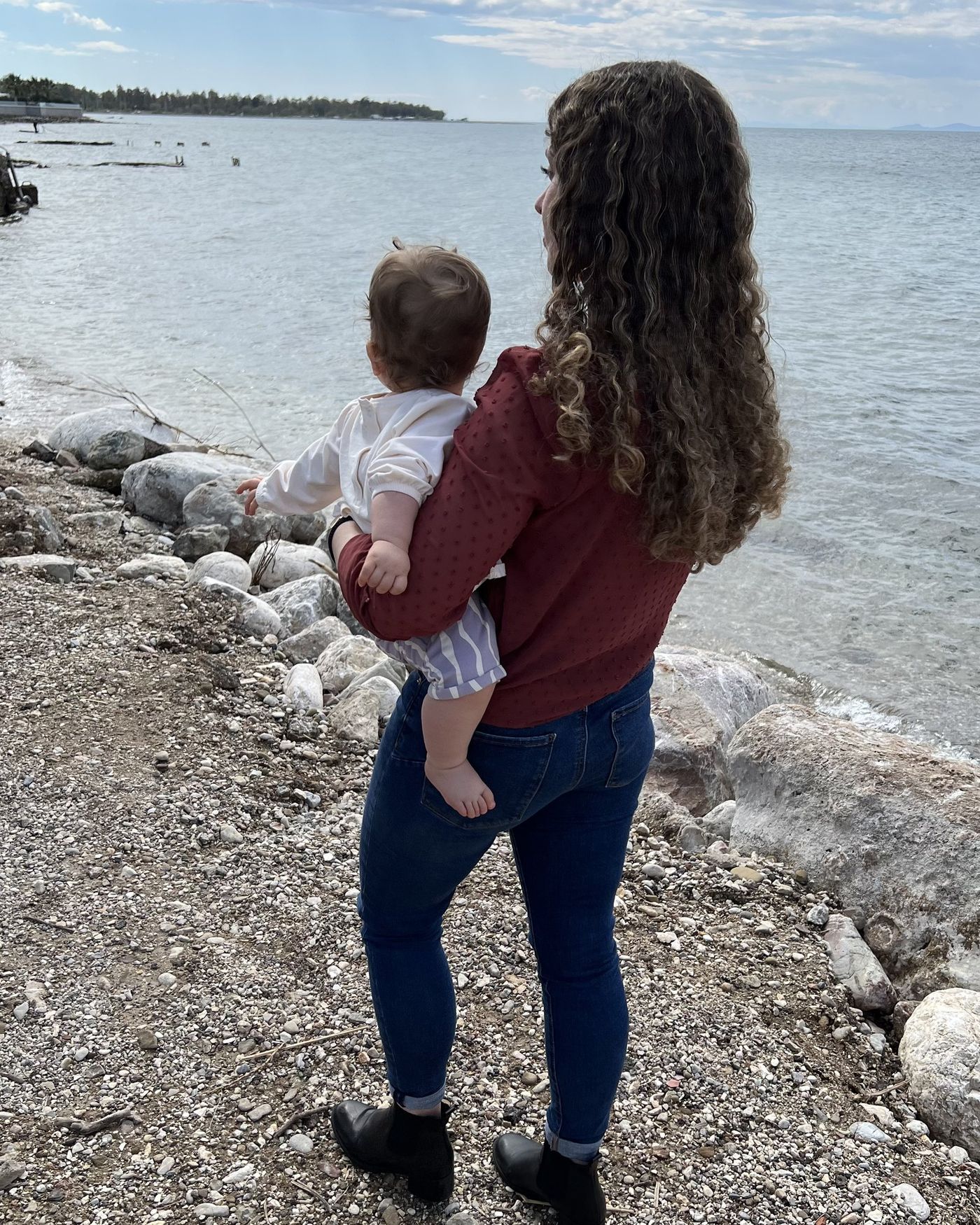 Mariangela holding her baby, looking out over the sea